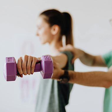 Person lifting a small weight assisted by a therapist