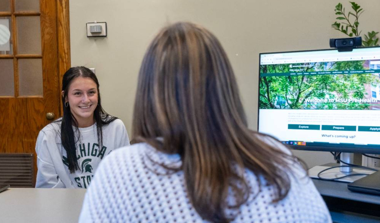 student sitting with an advisor in an office.